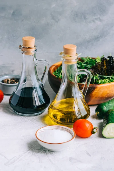 Cooking fresh salad, ingredients on table with olive oil and balsamic vinegar.