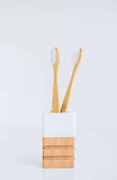 Bamboo toothbrushes in a wooden cup making with natural materials, isolated on white background