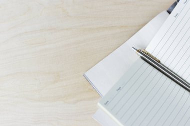 Defter ve kalem açık ahşap bir masada.