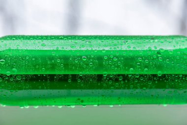 Bulanık ışık arka planında parlak yeşil plastik şişenin bir parçası