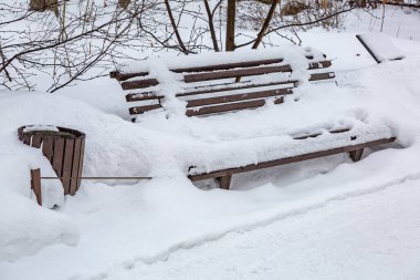 Kışlık şehir parkında karla kaplı ahşap bank