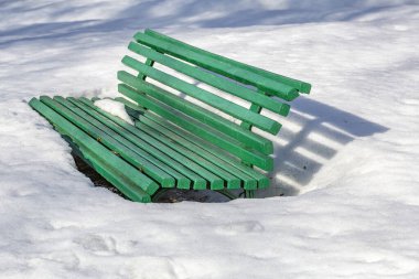 Kışlık şehir parkında karla kaplı ahşap bank