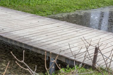 Şehir parkında dar bir dere boyunca rayları olmayan tahtadan yapılmış küçük bir köprü.