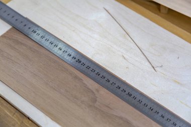 Uzun demir cetvel, bir marangozluk atölyesindeki ahşap tezgahta santimetre olarak ölçülmüş.