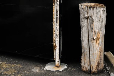 Siyah bir çitin arka planında çipler ve çatlaklar olan eski kuru bir kütük parçası.