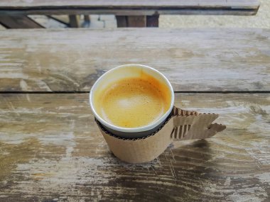 Kaba tahtalardan yapılmış bir masanın üzerinde taze demlenmiş kahve bardağı duruyor.