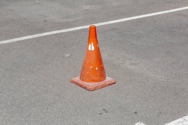 Asfalt yolda koni şeklinde plastik turuncu trafik işareti tehlike uyarısı yapıyor
