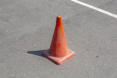 Asfalt yolda koni şeklinde plastik turuncu trafik işareti tehlike uyarısı yapıyor