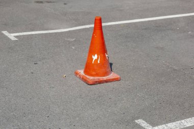 Asfalt yolda koni şeklinde plastik turuncu trafik işareti tehlike uyarısı yapıyor