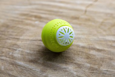 Parlak yeşil plastik top, ahşap bir yüzeyde ev buzdolabındaki nahoş kokuları emmek için.