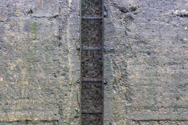 Çizik ve çatlaklarla kaplı gri beton duvarın desenli yüzeyi.