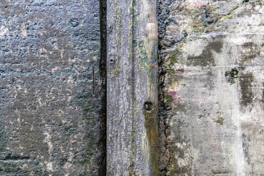 Çizik ve çatlaklarla kaplı gri beton duvarın desenli yüzeyi.