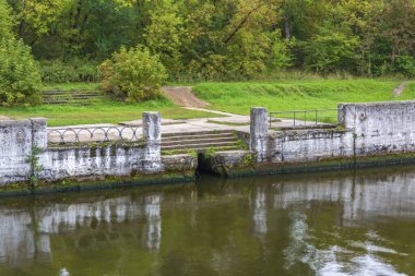 Sakin bir nehrin kıyısındaki tekneler ve küçük gemiler için yıpranmış rıhtım