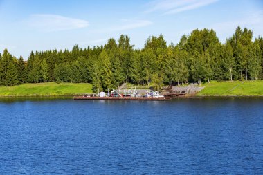 Sakin bir nehrin kıyısındaki tekneler ve küçük gemiler için yıpranmış rıhtım