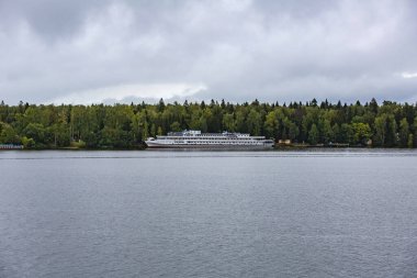 Nehir gezisinde beyaz üç güverteli gemi. Gemi yeşil orman tarafından demirlenmiş.