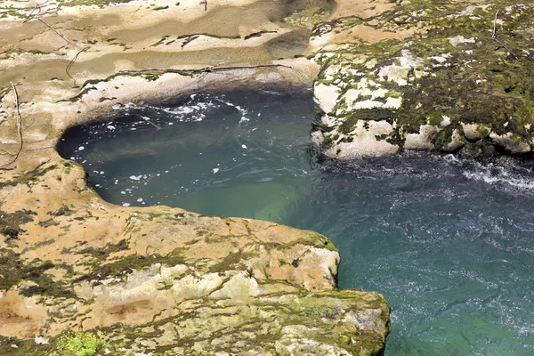 Water stroomt tussen stenen en mos — Stockfoto