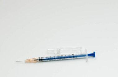 Beyaz zemin üzerinde cam ampul bulunan mavi şırınga