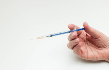 women's hand with blue syringe on white background