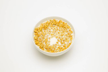 Beyaz arka planda beyaz bir fincanda sütlü buğday gevreği.