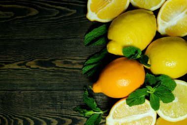 Koyu ahşap arka planda nane yapraklı limon ve yarım limon.