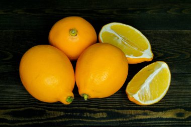Koyu ahşap arka planda olgun kaynak limonları, yukarıdan çerçeve şeklinde fotoğraflanmıştır.