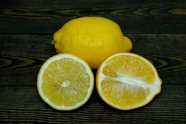 Whole lemons and half lemons on a dark wooden background