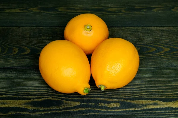 Koyu ahşap arka planda olgun kaynak limonları, yukarıdan çerçeve şeklinde fotoğraflanmıştır.