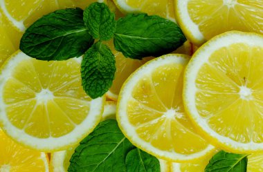 Parlak arka planda nane yapraklı doğranmış limonlar.