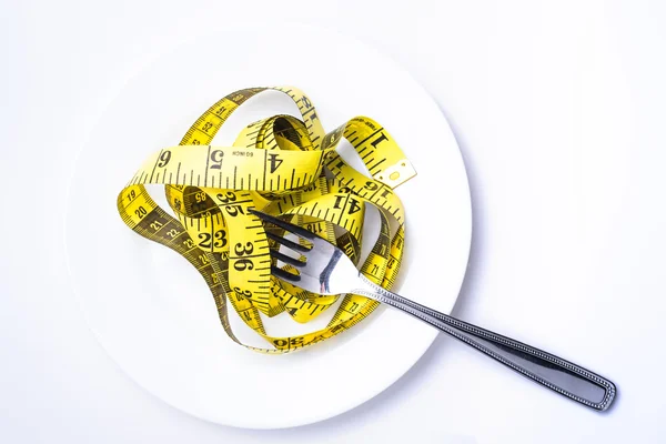 접시 다이어트의 개념으로 흰색 테이블에 고립 된 눈금자 — 스톡 사진