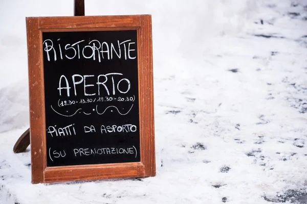 Pizarra fuera de un restaurante italiano abierto y nieve — Foto de Stock