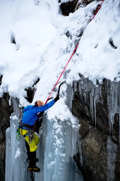 Brave ice climber climbing a iced waterfall in italian alps Royalty Free Stock Photos