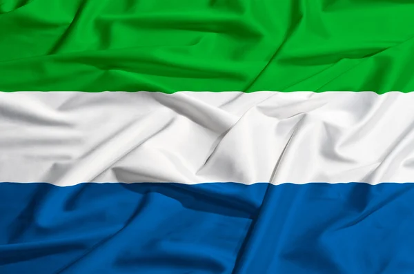 Bandera de Sierra Leona sobre una cortina de seda ondeando — Foto de Stock