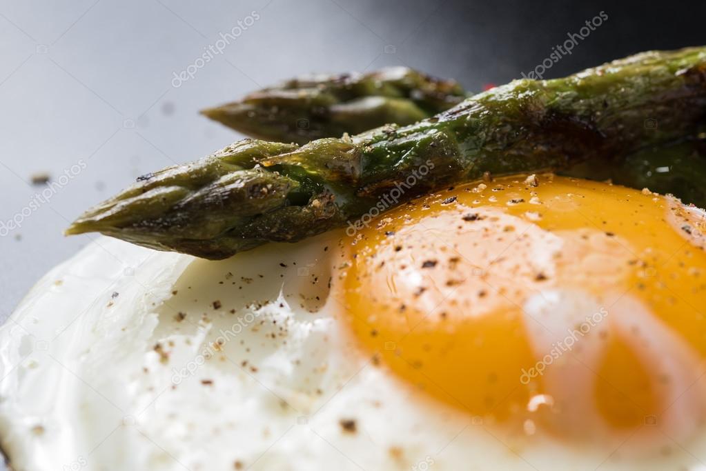 Fried egg and roasted asparagus in black plate