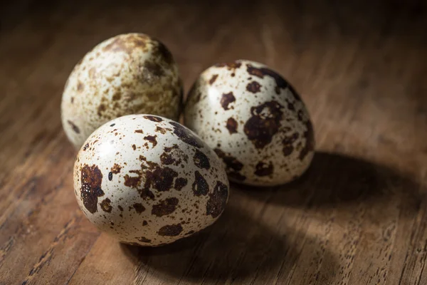 ダークウッドのテーブルに分離された 3 つのウズラの卵 — ストック写真