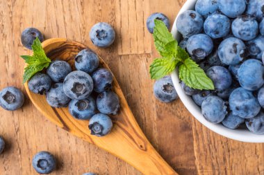 bir ahşap masa ve kase taze yaban mersini