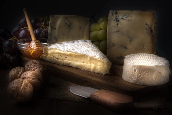 Wooden board with cheeses, grapes, nuts and honey — Stock Photo, Image