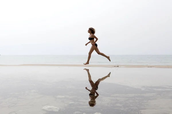 Hermosa atlética joven mujer corriendo por el mar. — Foto de Stock