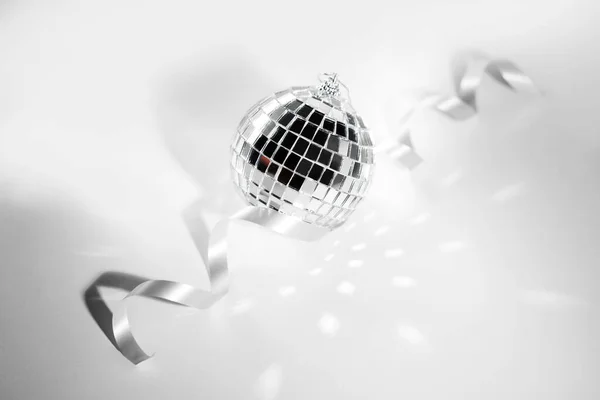 New Years disco ball on a light background with highlights and ribbon.