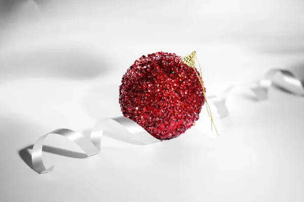 Πρωτοχρονιάτικη κόκκινη μπάλα σε ανοιχτό φόντο με κορδέλα. — Φωτογραφία Αρχείου