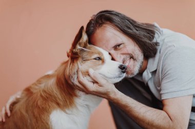 Yakışıklı yetişkin bir adam köpeğe sarılıyor..