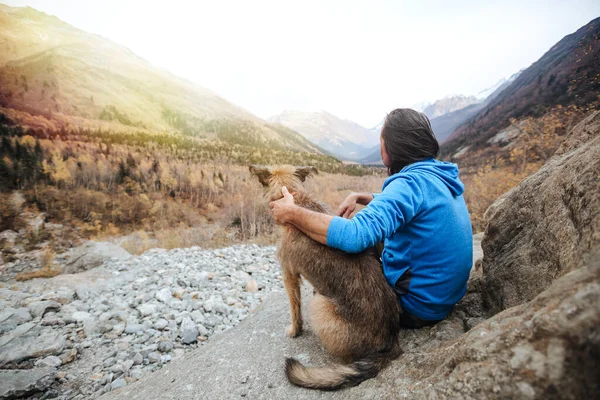 A man and his dog on a background of mountains. — Stock Photo, Image