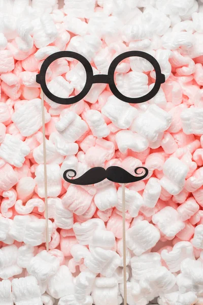 Maskerade aus Papier, festliche Brille und Schnurrbart liegen auf dem Hintergrund. Ein verspieltes Porträt. — Stockfoto