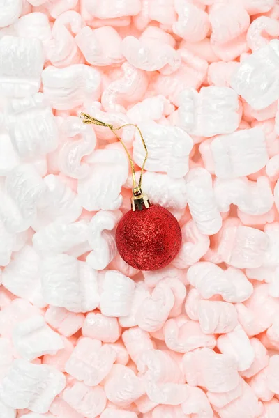 Bola de Natal vermelho brilhante em um fundo branco-rosa. — Fotografia de Stock