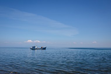 Su Baykal Gölü mavi gökyüzünde yalnız teknede
