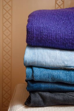 Basit bir gardırop, kıyafet dolabı. Teke tek katlanmış kot pantolon ve sonbahar sezonunda, yakın çekimde mor bir kazak..