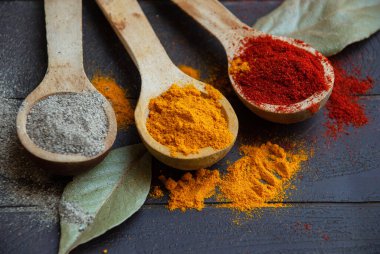 Paprikalı üç tahta kaşık, zerdeçal tozu ve karabiber. Gıda sosları kapanıyor..