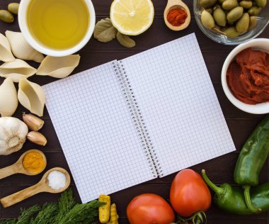 Yiyecek malzemeleriyle çevrili bir defter aç. Yemek tarifleri için mutfak geçmişi. Pişirmek için taze sebze ve malzeme çerçevesi. Market alışveriş listesi, yemek tarifi kitabı, diyet veya vejetaryen yemeği..