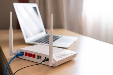 Yönlendiricide seçici odaklanma. Arka planda bulanık bilgisayar olan çalışma masasındaki internet yönlendiricisi. LAN kablo bağlantısı ile fiber hattından hızlı ve yüksek hızlı internet bağlantısı.