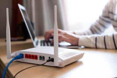 Yönlendiricide seçici odaklanma. Bulanık adamla çalışan bir masadaki internet yönlendiricisi arka plandaki kabloyu bağla. LAN kablo bağlantısı ile fiber hattından hızlı ve yüksek hızlı internet bağlantısı.