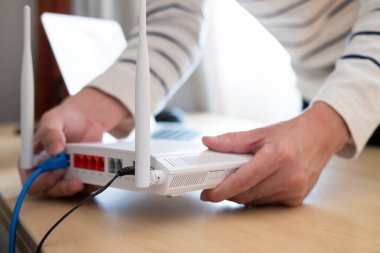 Yönlendiricide seçici odaklanma. Bulanık adamla çalışan bir masadaki internet yönlendiricisi arka plandaki kabloyu bağla. LAN kablo bağlantısı ile fiber hattından hızlı ve yüksek hızlı internet bağlantısı.